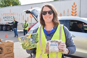 Volunteer holding up peppers and walnuts at a Mobile Pantry