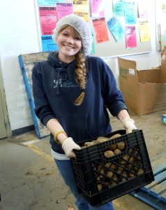 Rachel Rounds hefts one of many boxes of potatoes she and her friends sorted on Valentine's Day.