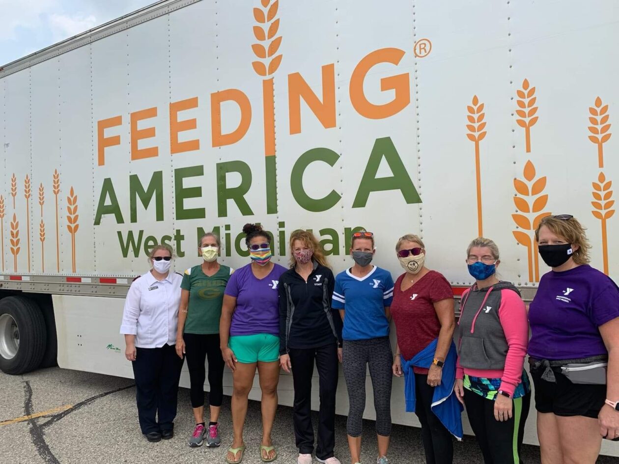 Volunteers stand in front of a food bank truck