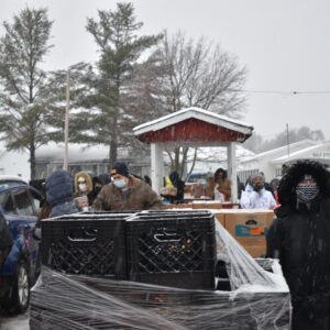 Volunteers load cars with food amid a snowy backdrop
