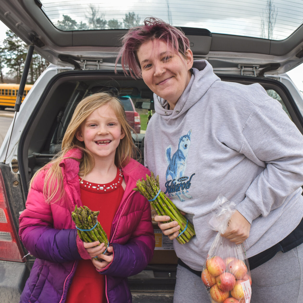 A mom and her daughter hold asparagus at a Mobile Pantry