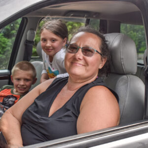 Teri sits in her car with two of her grandkids
