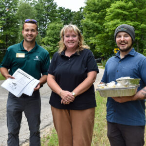 Three volunteers pose as they wait to pass out recipe samples to neighbors in line at a Mobile Food Pantry