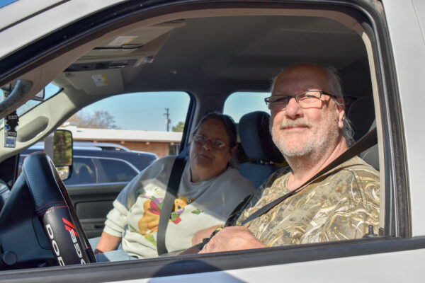 Kathy and Gary smile as they sit in their car