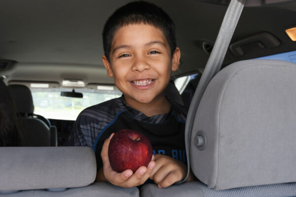 boy sitting in car holding an apple