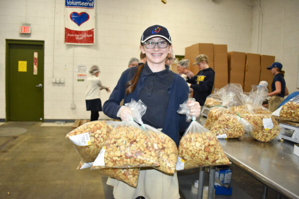 Reclamation volunteer smiles while holding bags of croutons