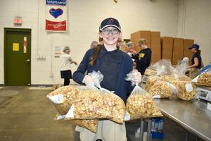 Reclamation volunteer smiles while holding up bag of croutons