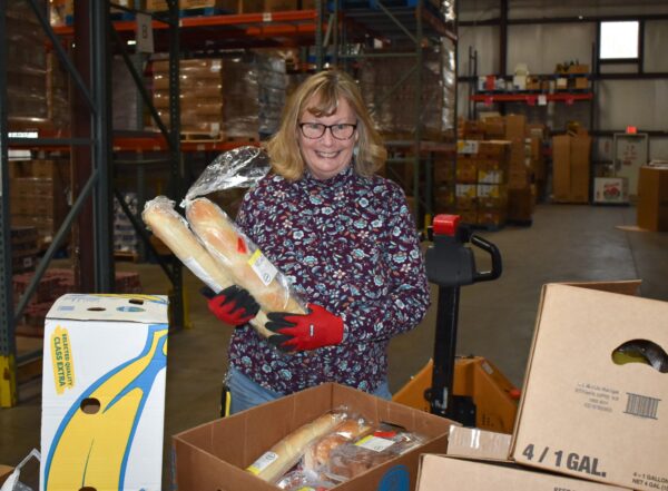 Jean smiles while holding up bread as she volunteers in reclamation