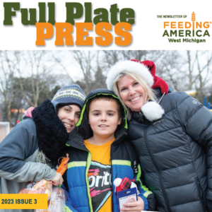 Newsletter cover image with three people smiling wearing winter clothing at a holiday event
