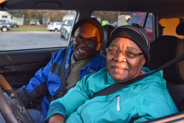 Man and woman smiling while waiting in their car at a Mobile Food Pantry
