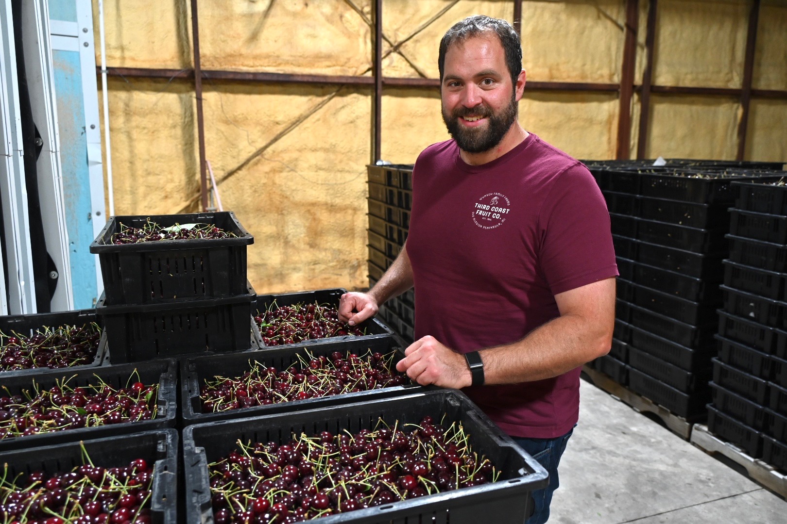 Isaiah Wunsch of Third Coast Fruit Co next to crates of cherries.