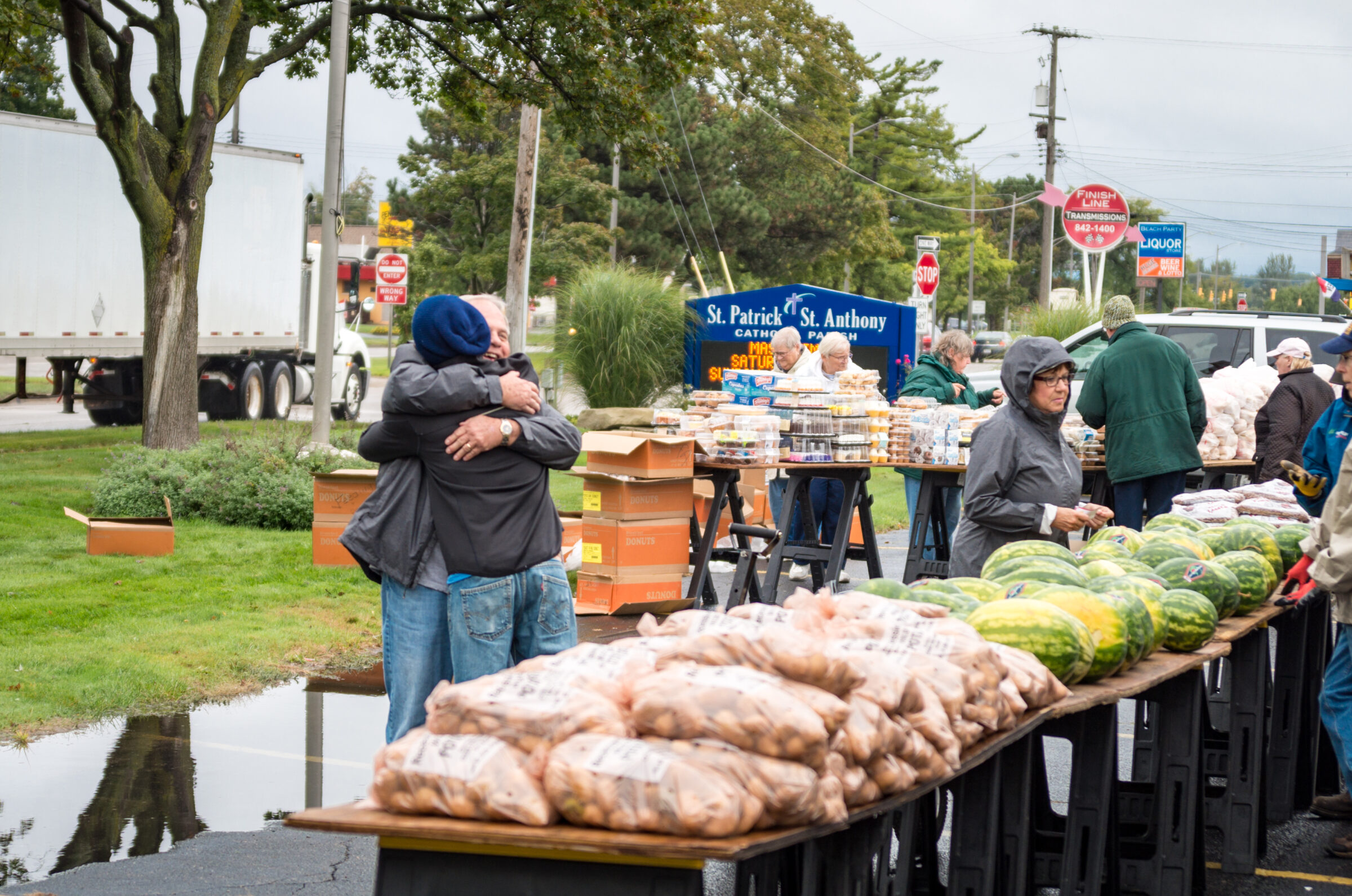 Two individuals hugging at a mobile food distribution.