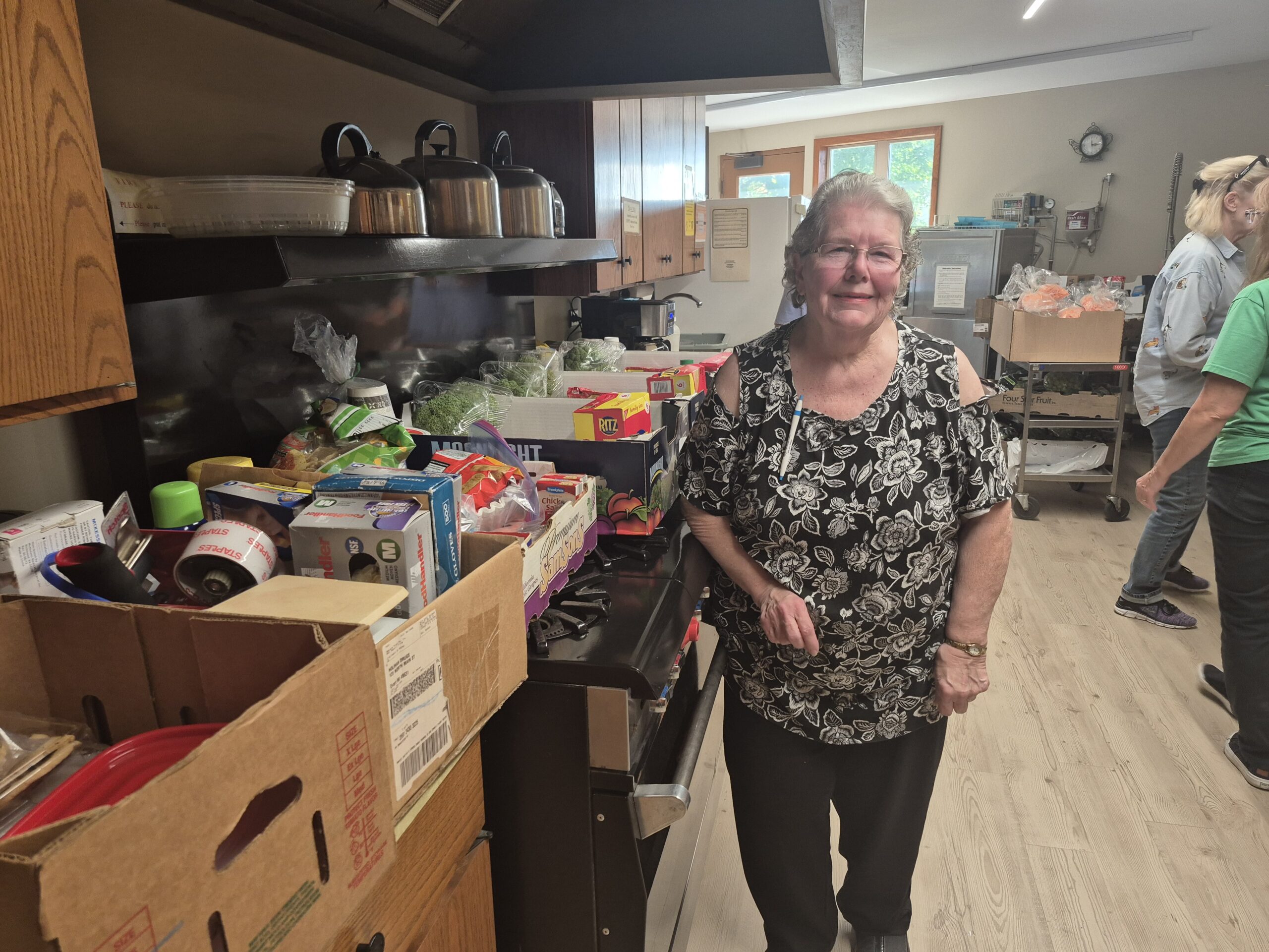 Donnie Sue Johnson, coordinador de la despensa móvil de alimentos en la Iglesia Metodista Unida de Evart, está junto a cajas de alimentos preparadas para los vecinos.