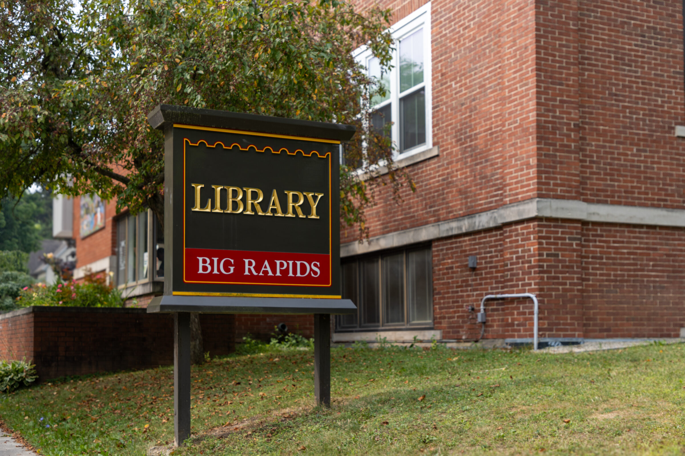 The Big Rapids Community Library sign and the building’s brick exterior welcoming neighbors while serving Gather 2 Grow meals. 