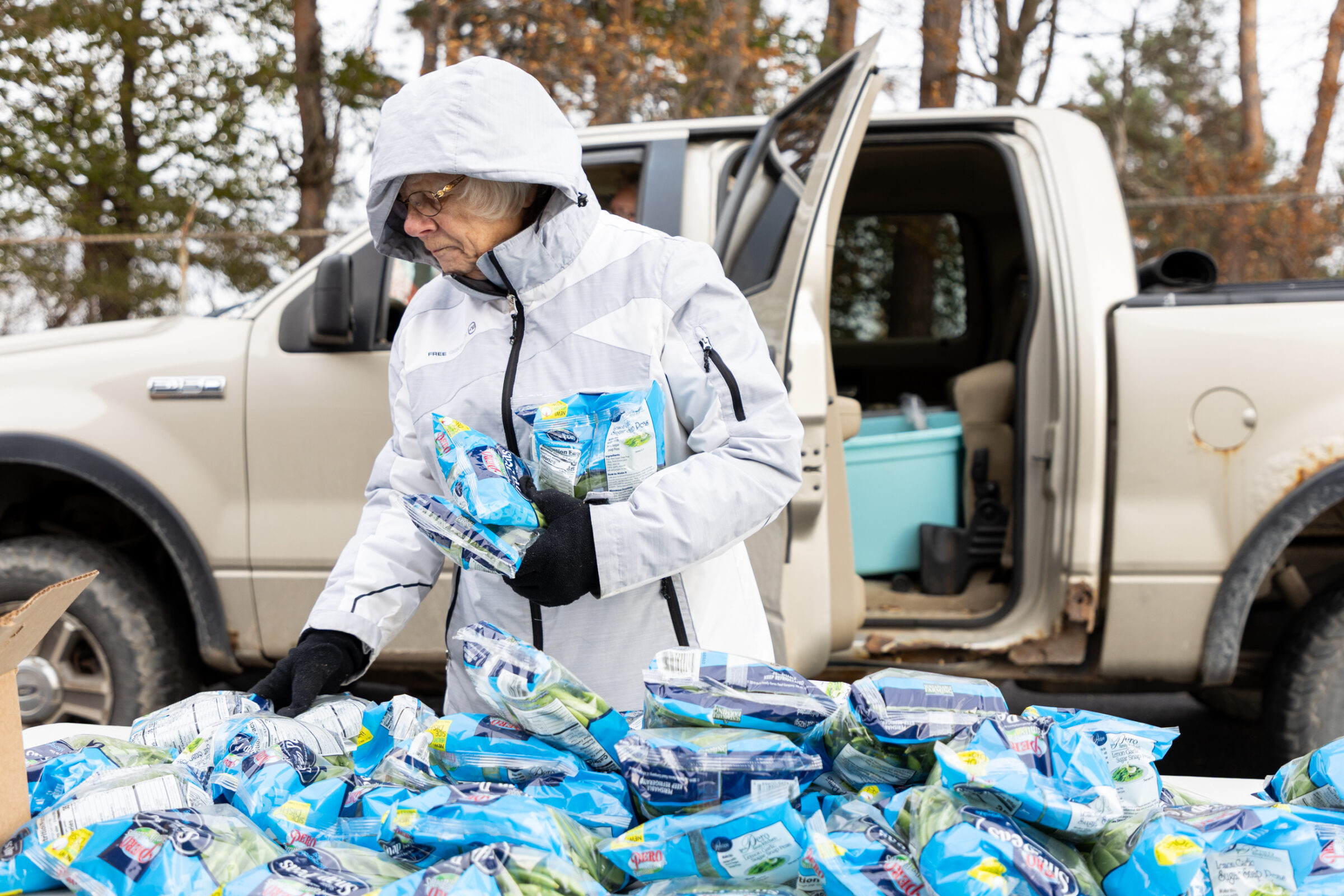 A mobile food pantry volunteer gathering snap peas to put in neighbors' cars.