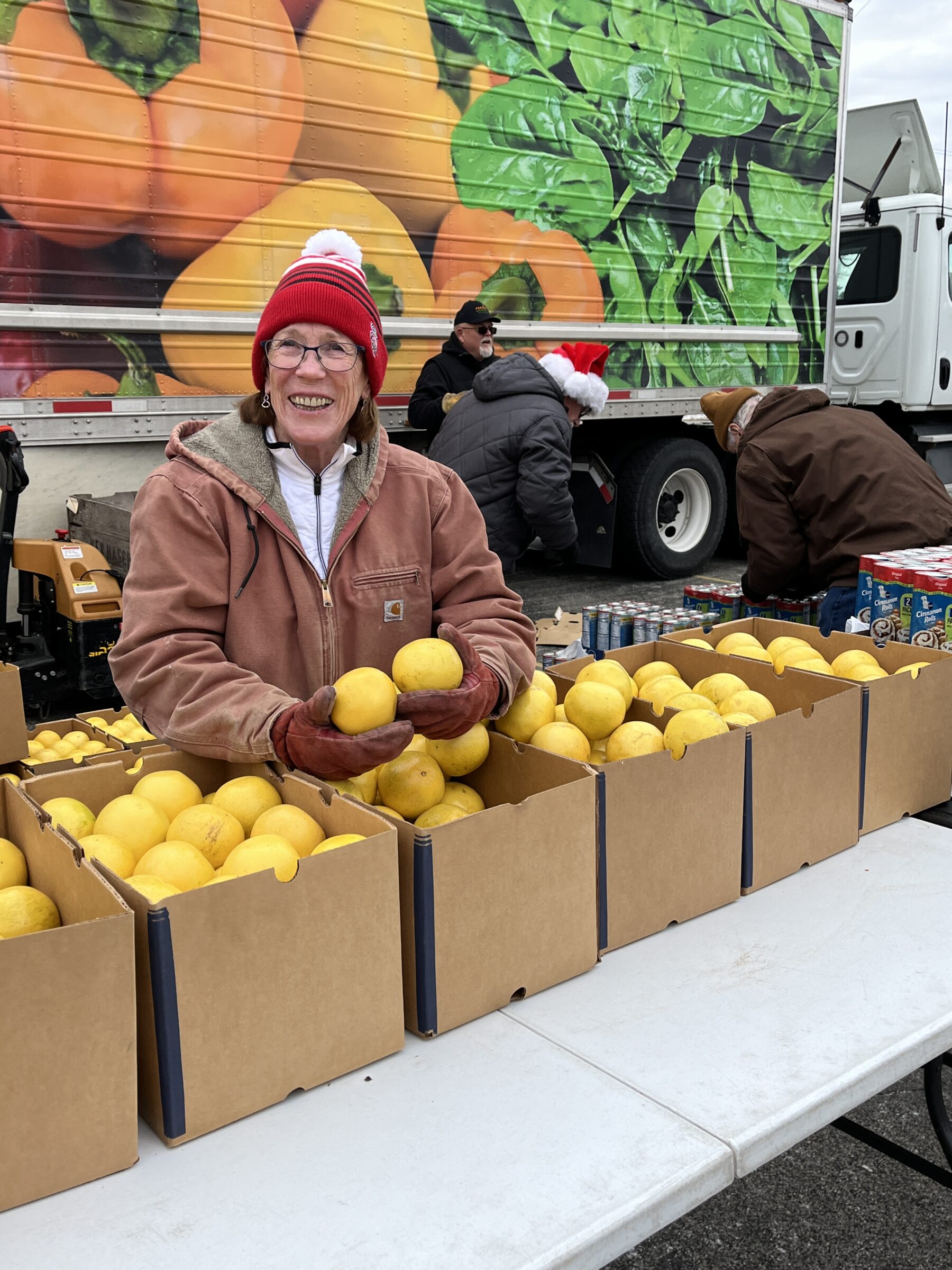 Smiling volunteer behind boxes of produce at a mobile food pantry. 