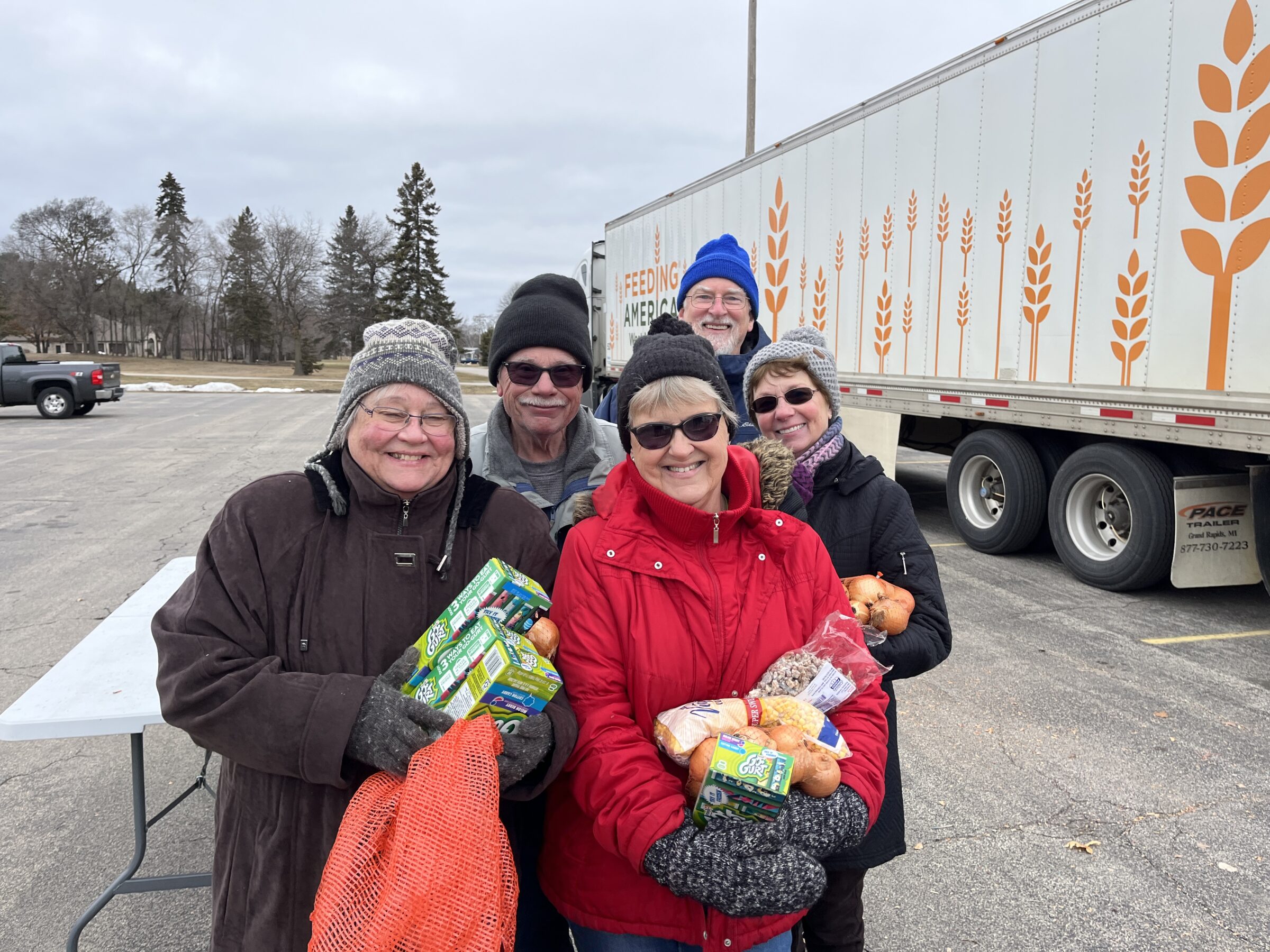 Volunteers at The Greater Marinette-Menominee YMCA holding food items and smiling. 