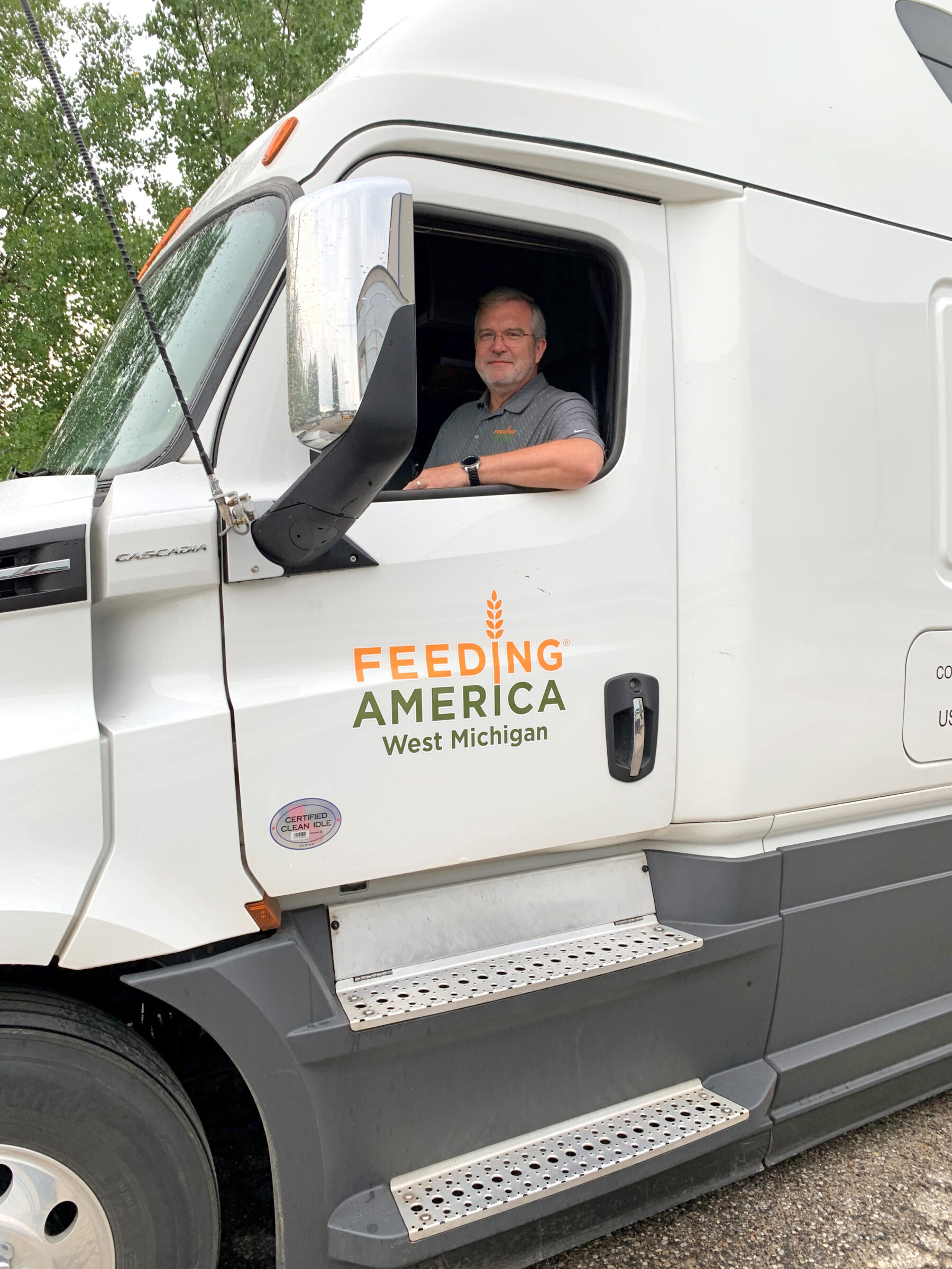 Feeding America West Michigan CEO and President Ken Estelle sitting in the driver's seat of a Feeding America West Michigan truck. 