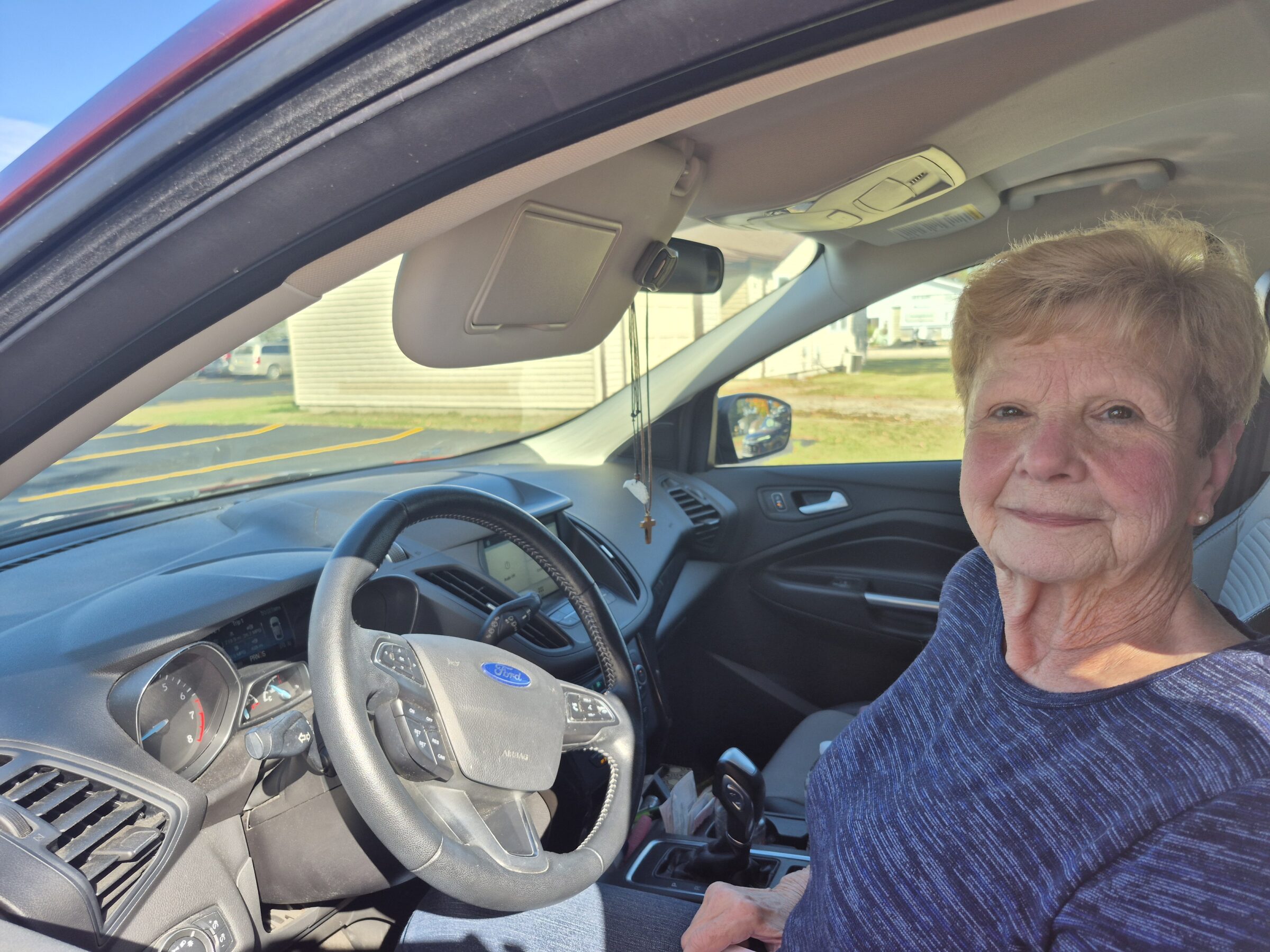 A woman sitting in her car and smiling. 