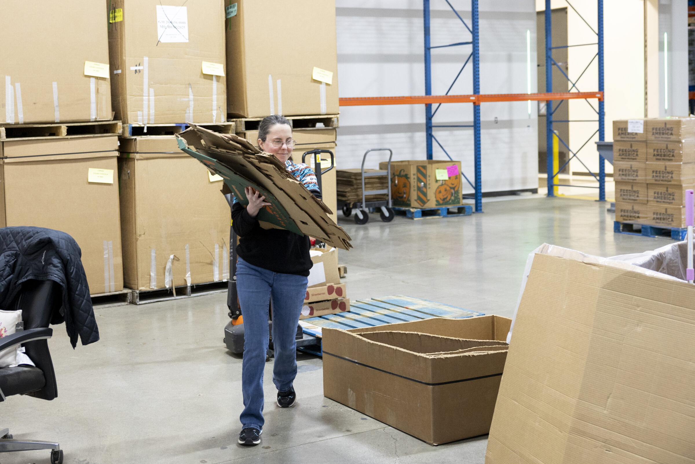 Feeding America West Michigan employee carrying cardboard for recycling. 