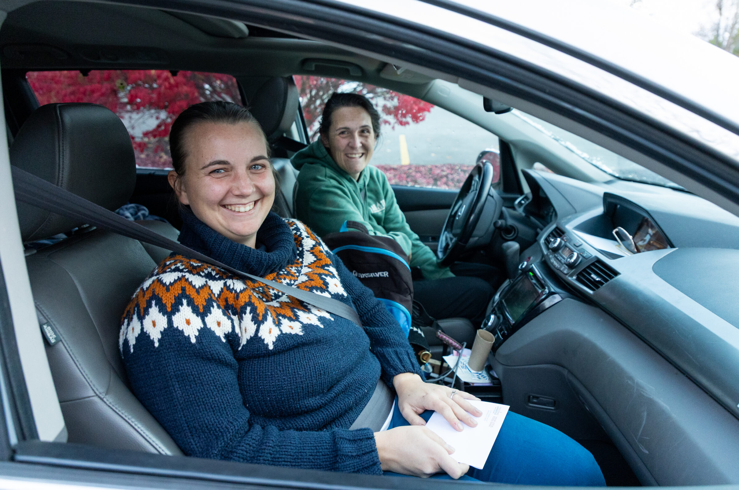 Two smiling women sitting in a car. 