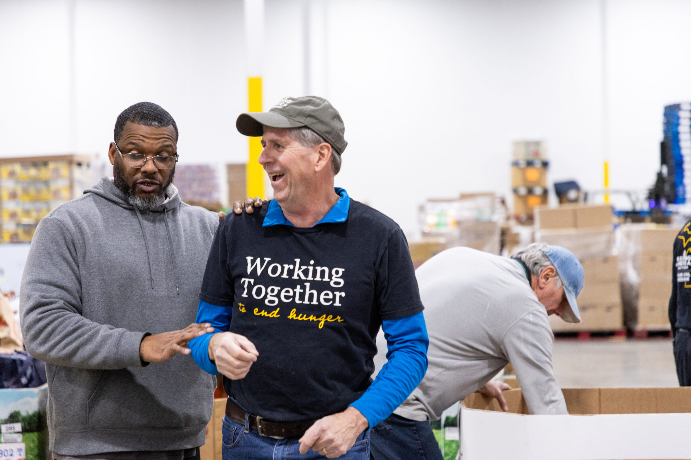 Feeding America West Michigan staff chatting with Tuesday regular volunteer while he laughs.