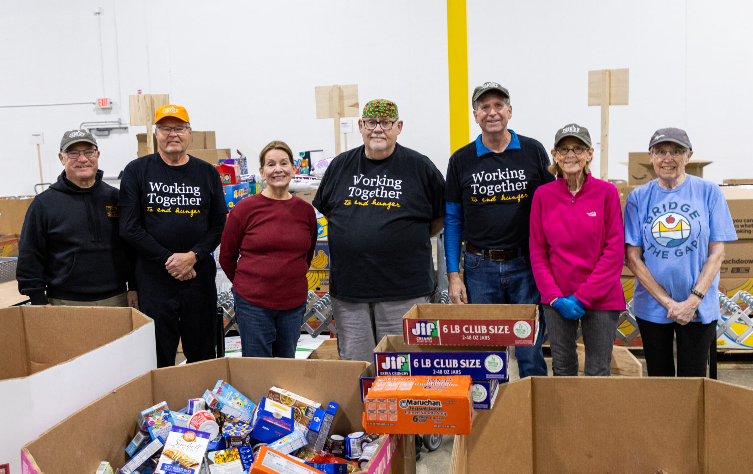 Feeding America West Michigan Tuesday regular volunteers standing in a line and smiling.