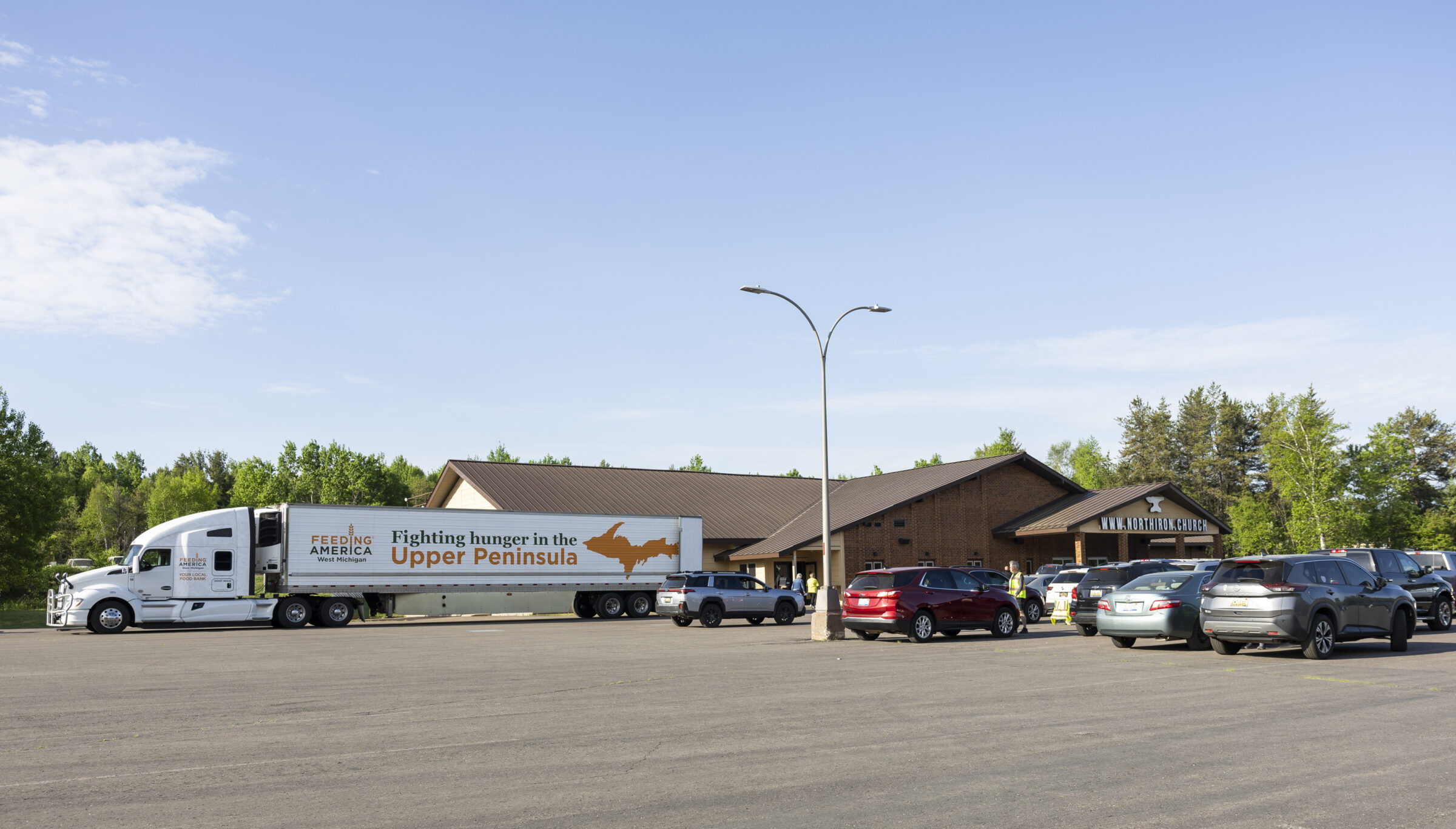 North Iron Church parking lot filled with cars and a Feeding America West Michigan truck. 