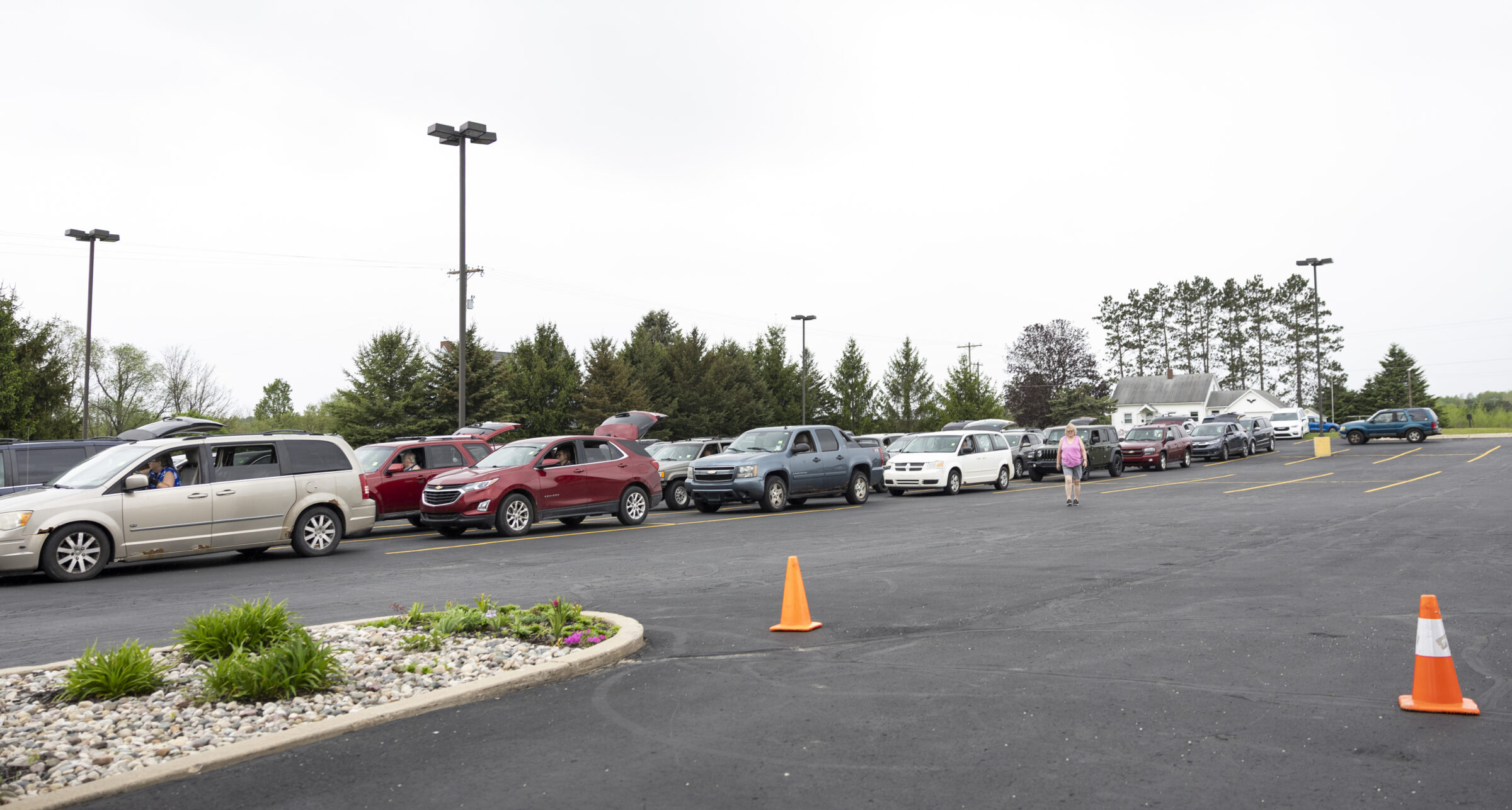 Several cars in a line in a parking lot for a mobile food pantry distribution.