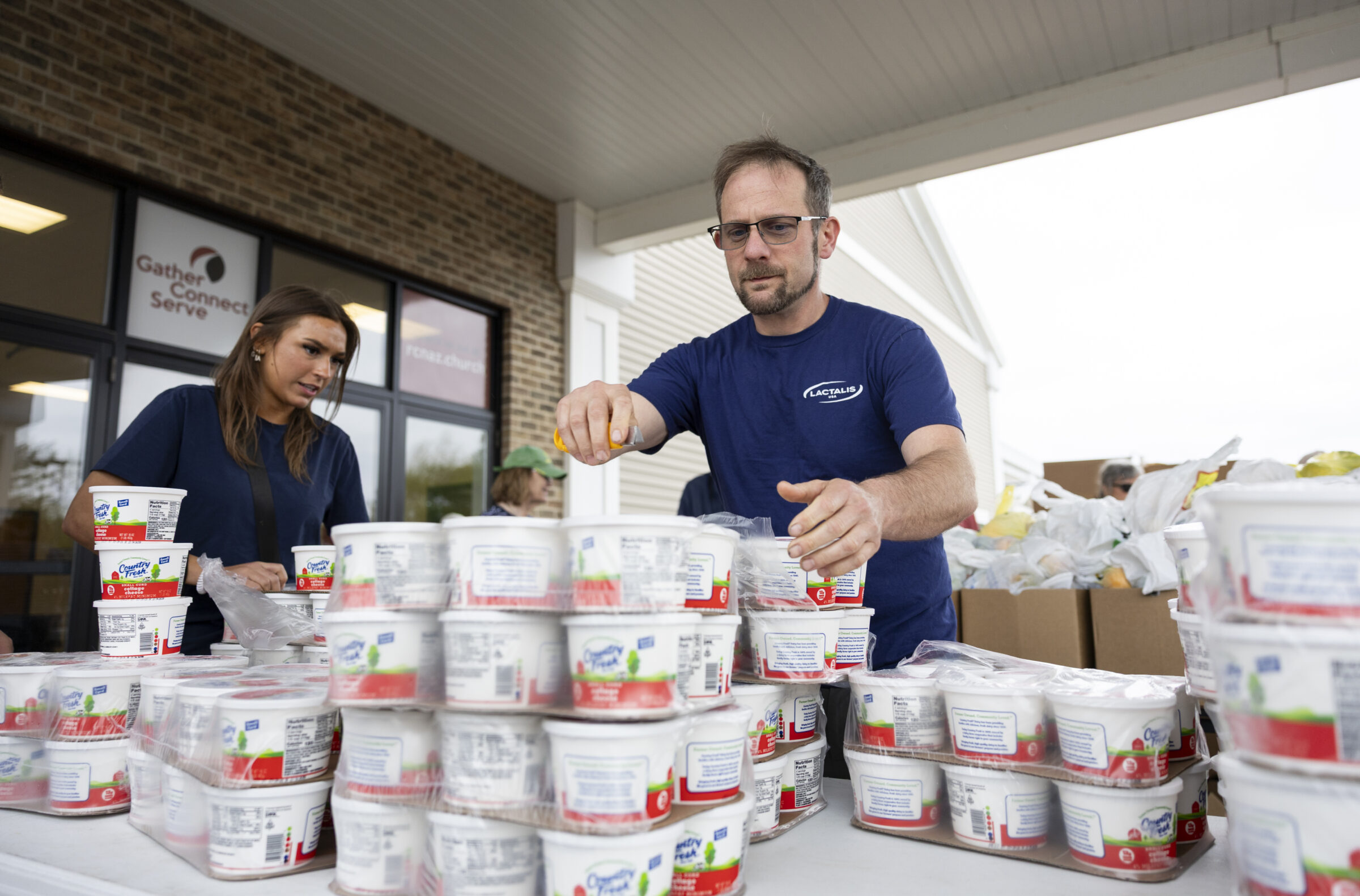 A volunteer from the company Lactalis arranges some small tubs of a Country Fresh product.