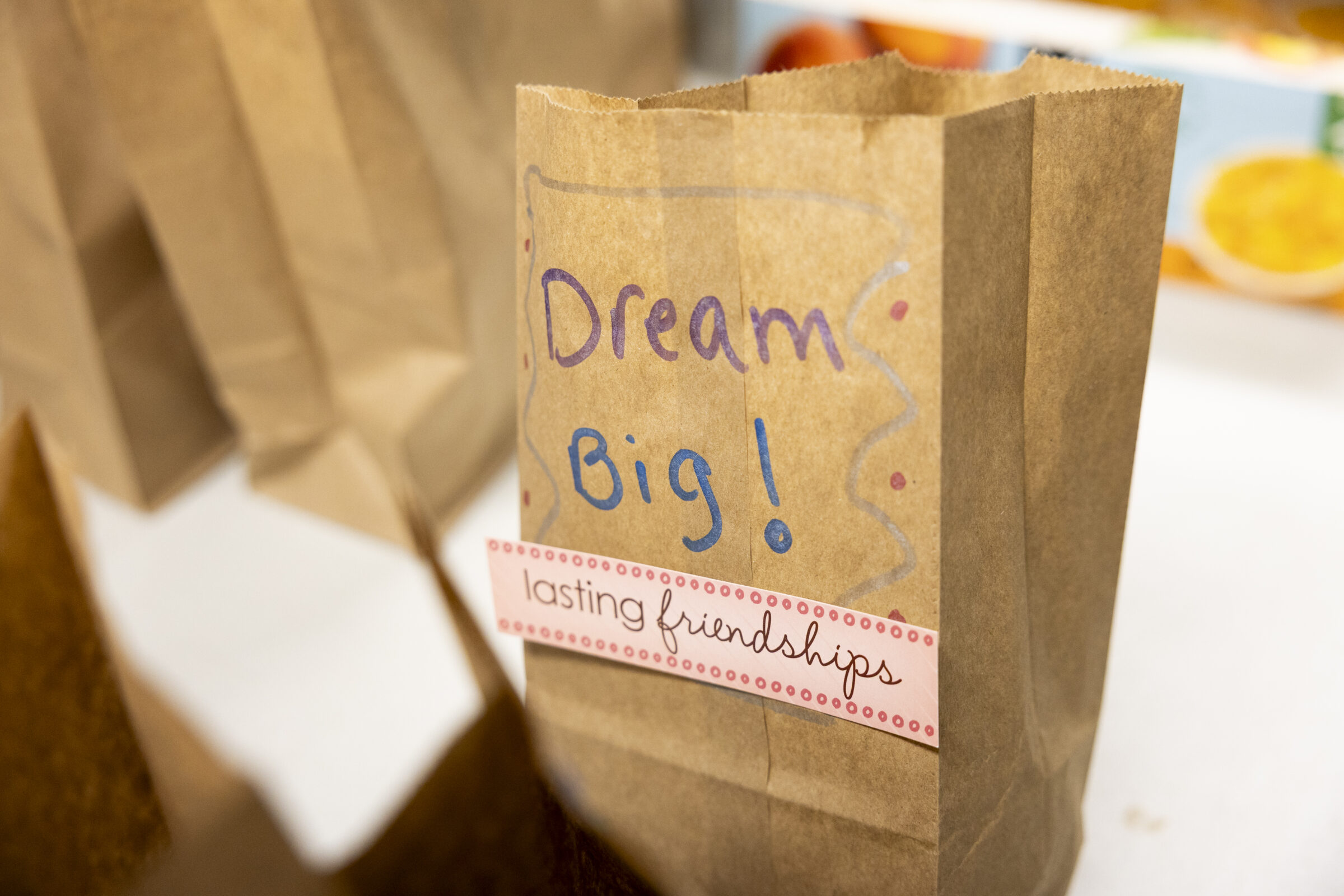 A brown paper lunch bag that says  "Dream Big" and "Lasting friendships" on it. 