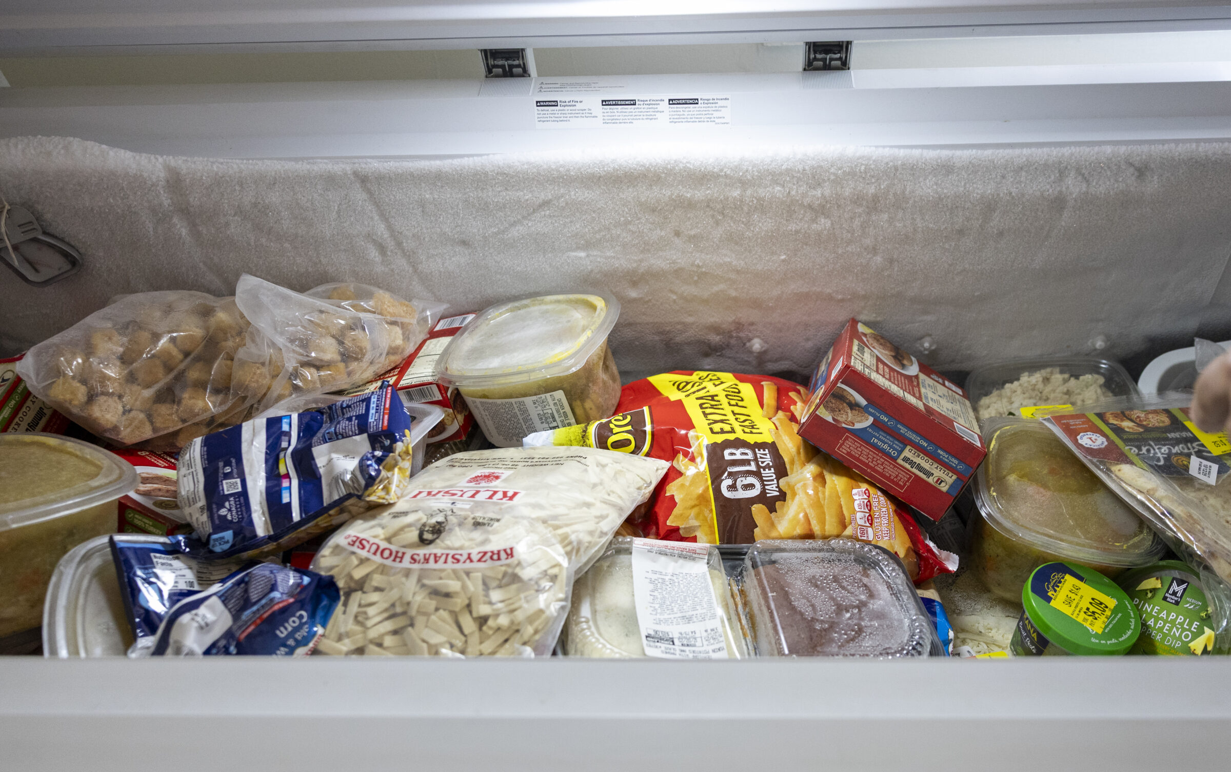A freezer filled with bags of frozen food items.