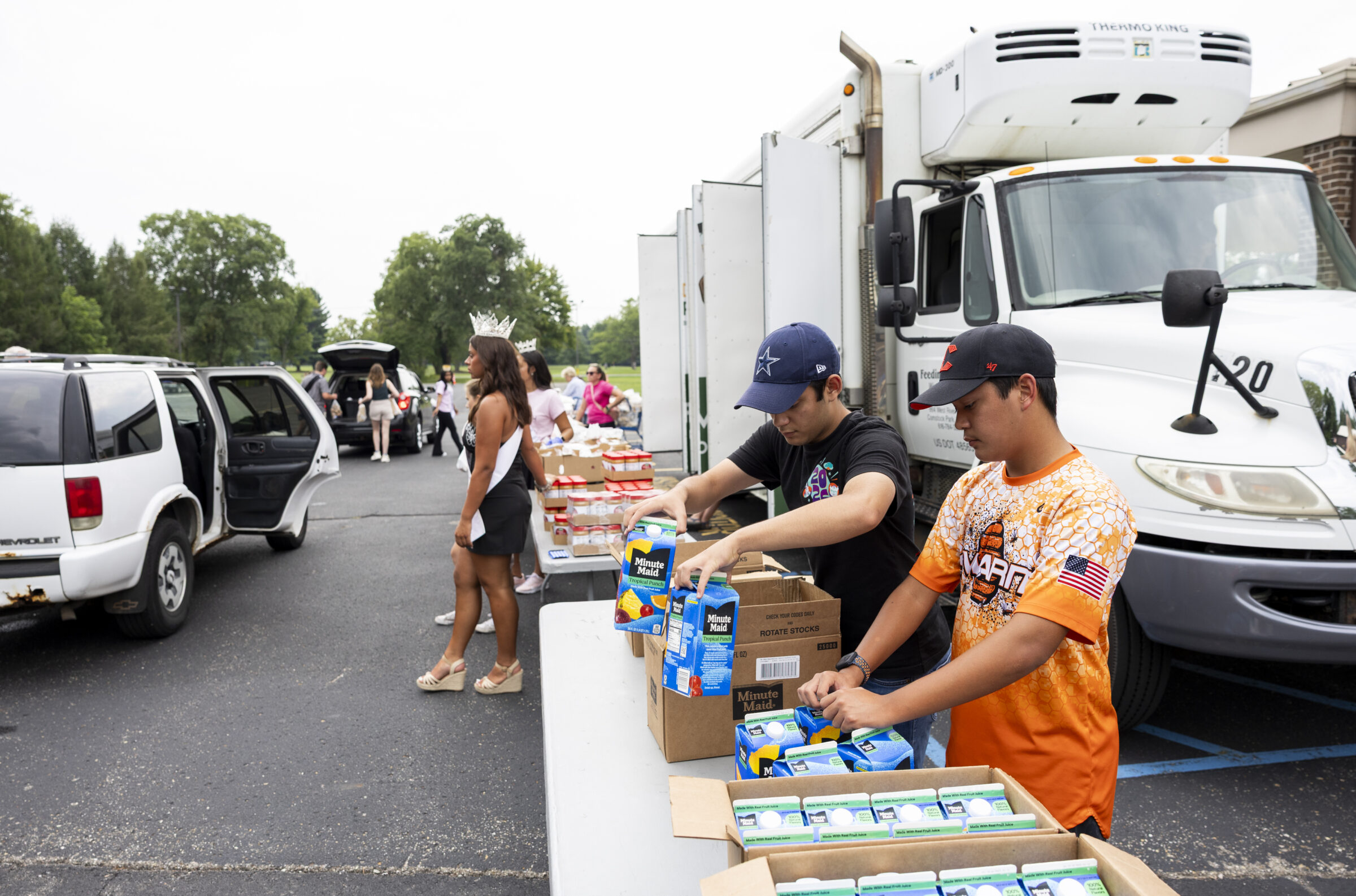 Several volunteers standing at a table, sorting out various food items.