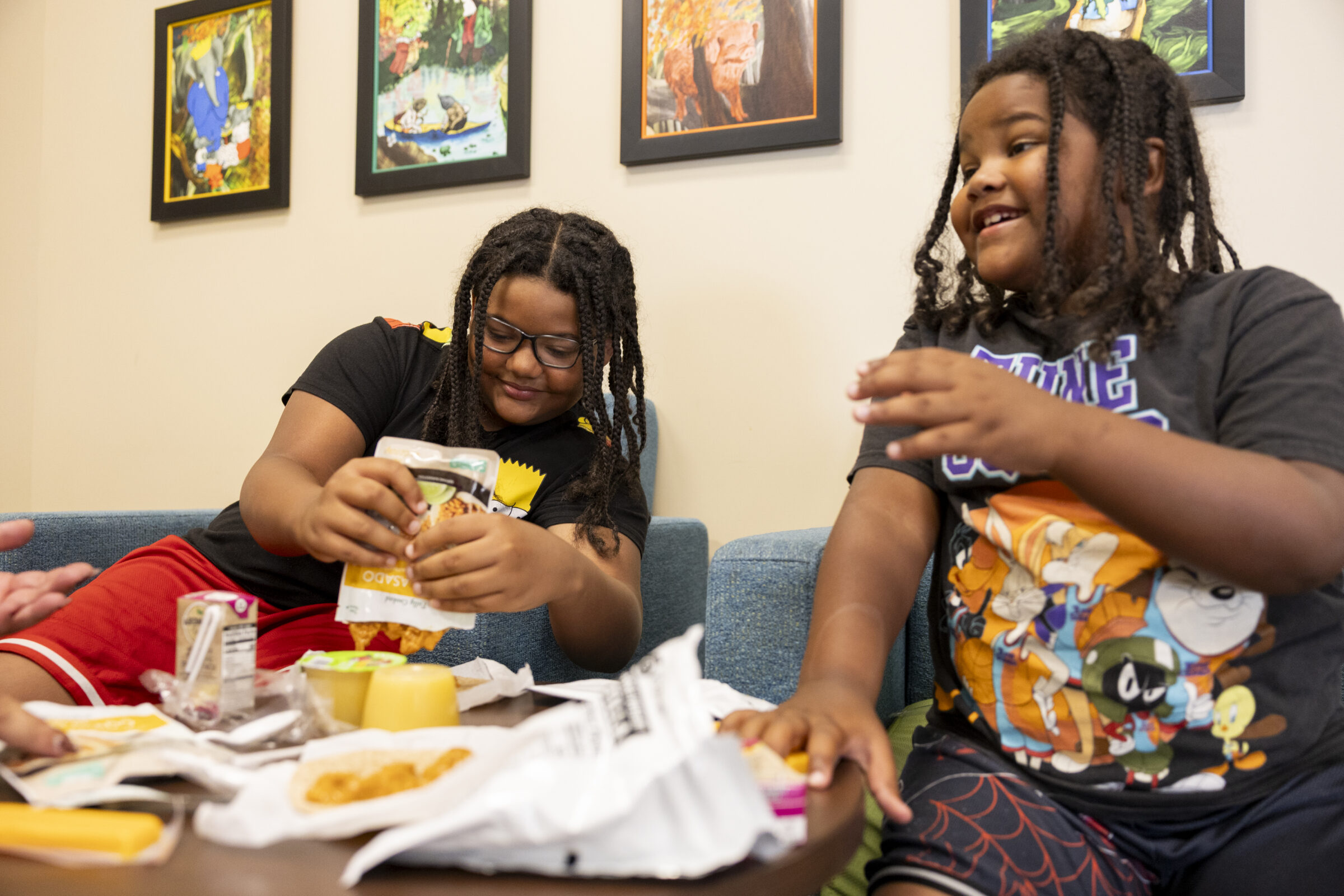 Two boys smiling while sitting down together and eating lunch. 