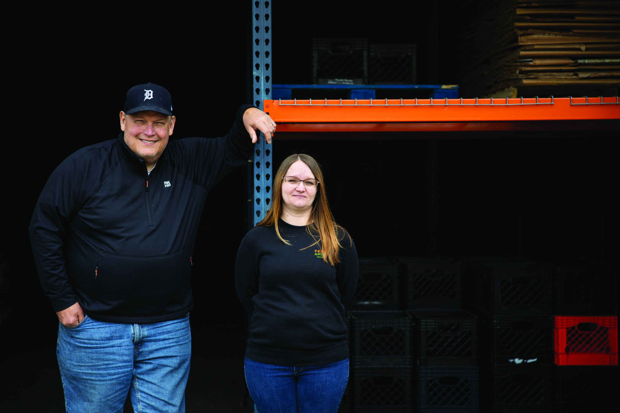 Feeding America West Michigan food bankers Rick and Kristy standing in front of a warehouse shelf.