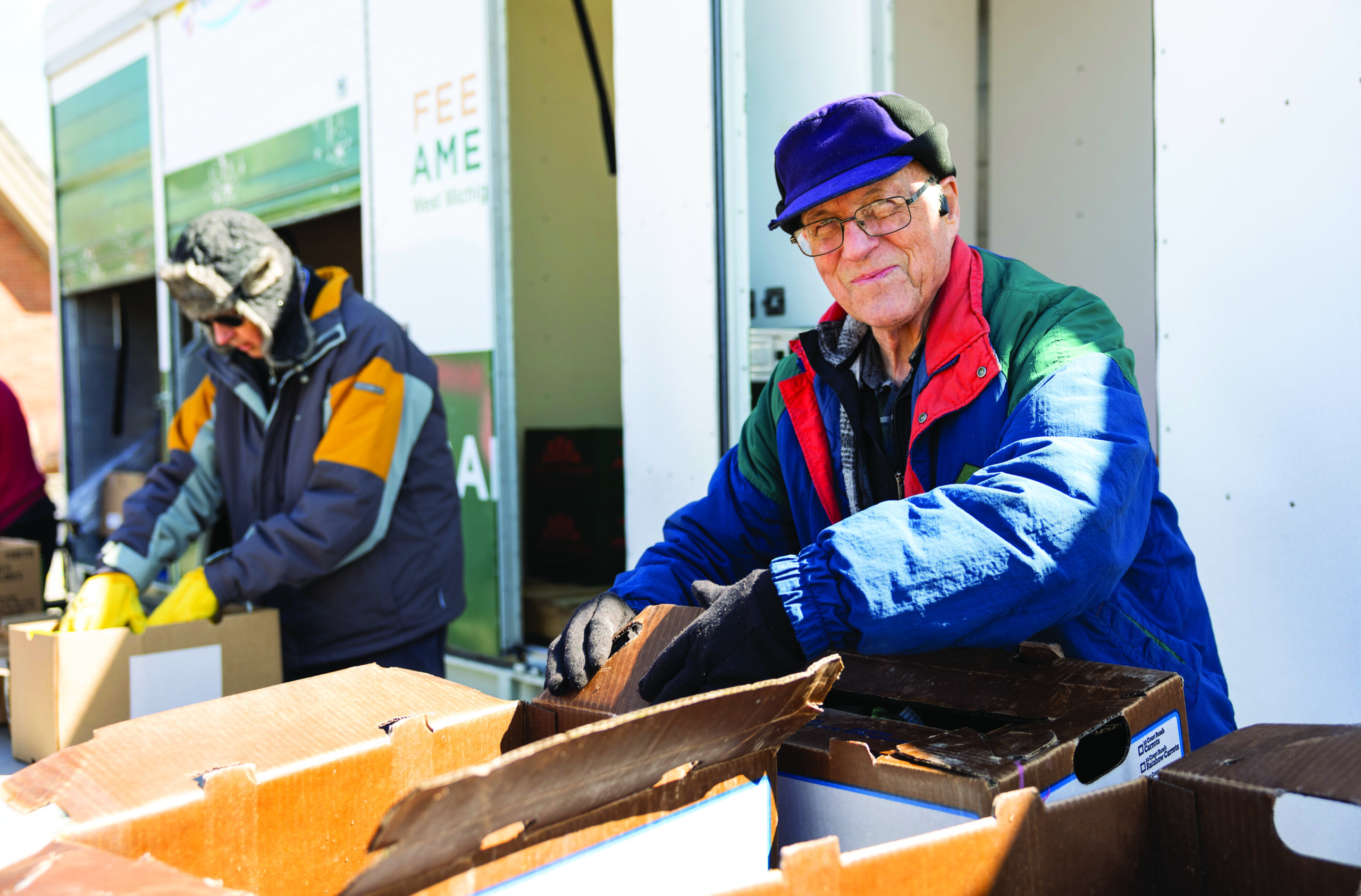 Mobile pantry coordinator Roger smiling at the camera. In is behind a table fill of boxes.