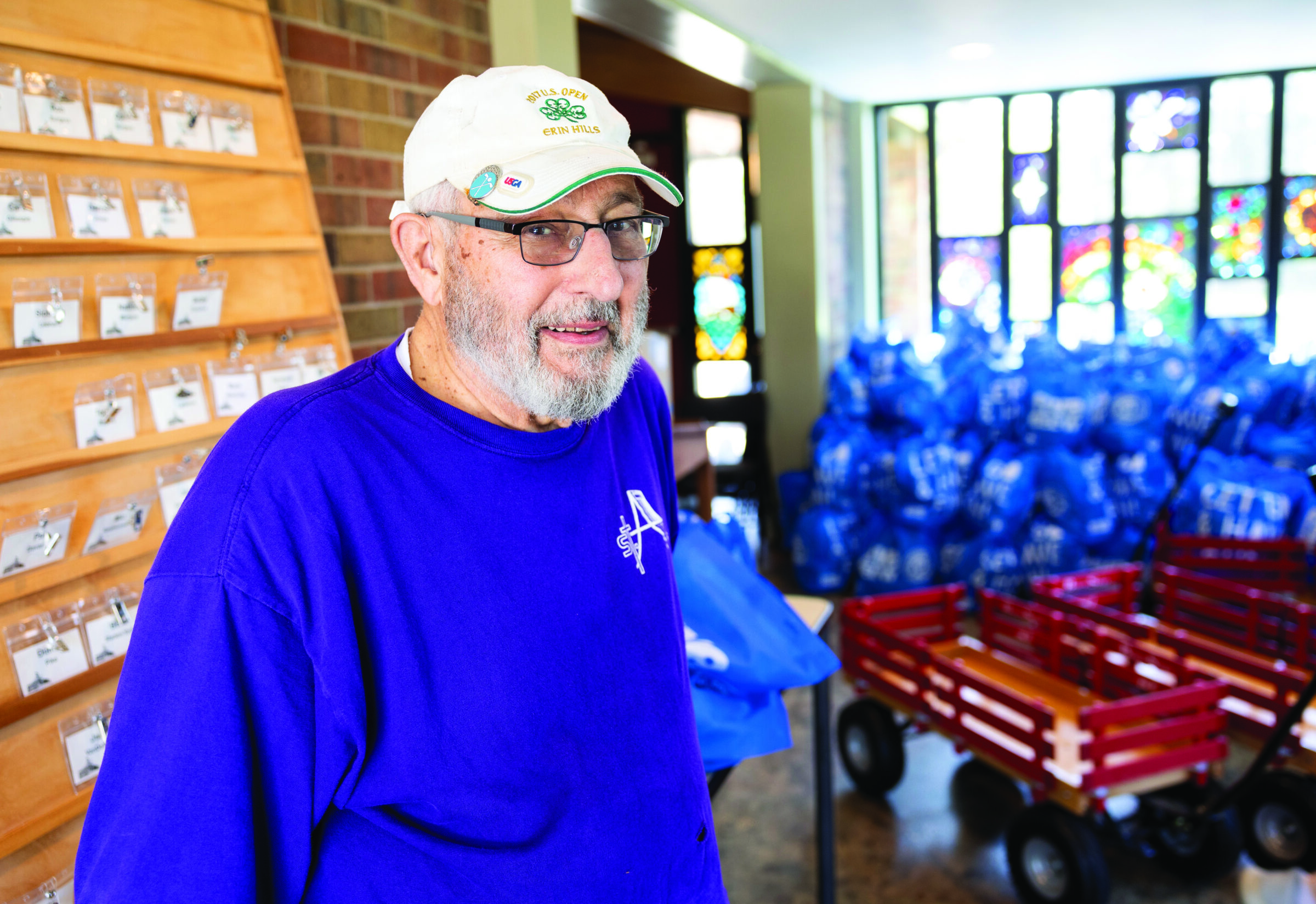 Pantry coordinator Les smiles in the foreground. Behind him, there are wagons and reusable bags filled with food.