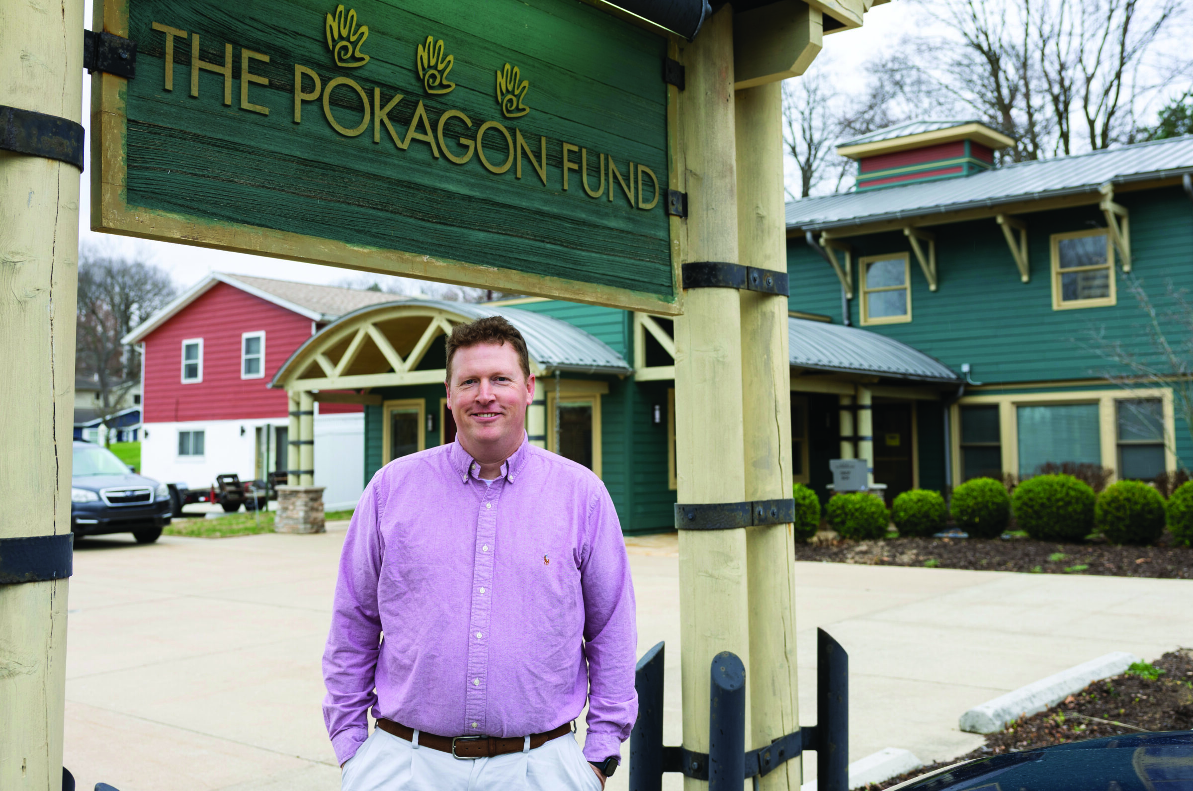 Pokagon Fund executive director, Dan Petersen, smiling while standing beneath The Pokagon Fund's sign.