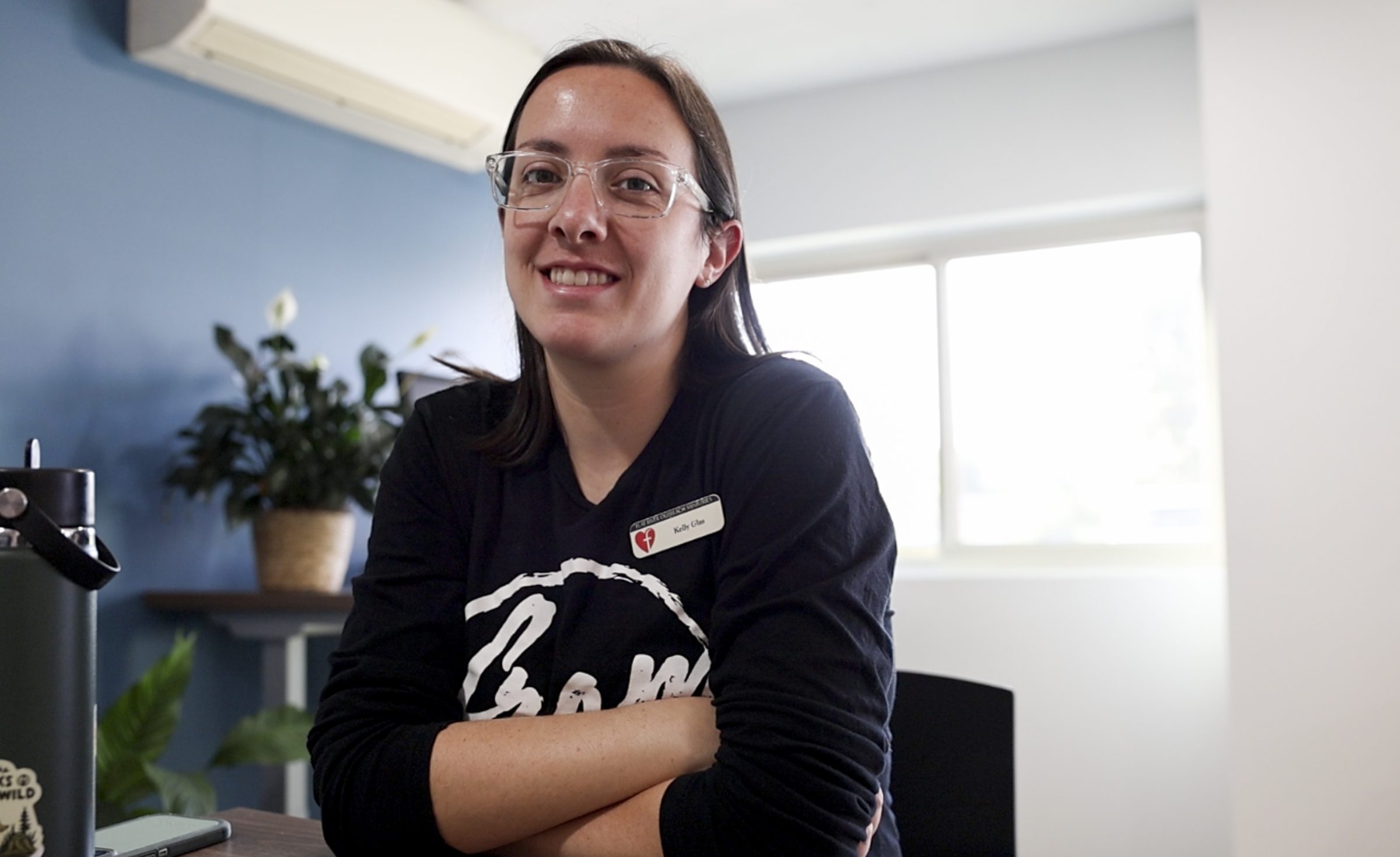 Program manager Kelly smiles while sitting at a desk at Flat River Outreach Ministries.